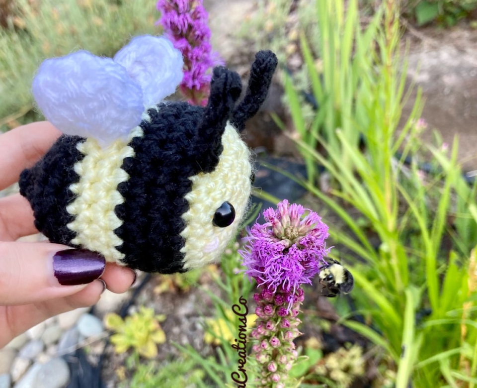 Crochet bee in front of flowers